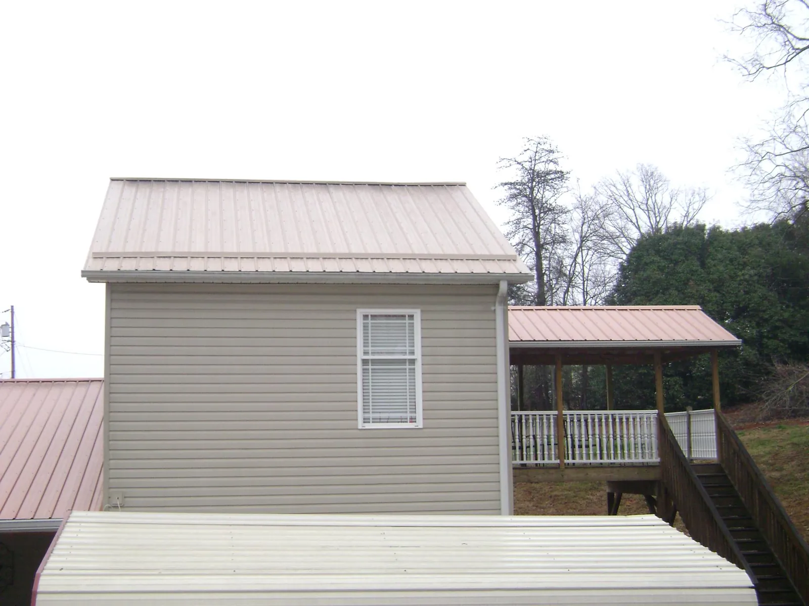 Tan metal roofs on a two story addition and attached porch, from a Roof Replacement job in South Haven
